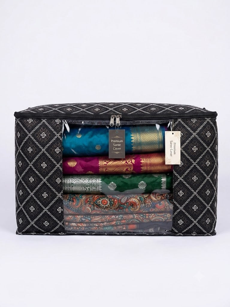 A black zippered fabric storage bag with a white geometric diamond pattern, shown filled with folded colorful sarees. A white paper tag is attached to the zipper.